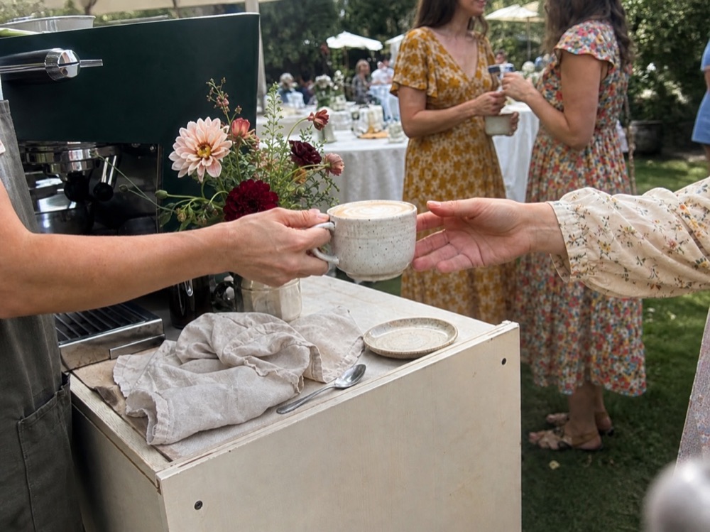 A handmade latte being served at an intimate garden gathering